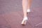 Female legs in white shoes high heels. Stepping young woman. View from the back.