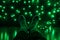 Female legs in wool socks in front of a festive wall decorated with green Christmas lights