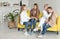 Female lesbian couple with their attractive daughers at home. Lesbian family in casual clothes sitting on yellow sofa