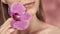 Female lips with delicate pink lipstick and orchid flower closeup on a pink blurred background. A beautiful white smile