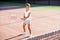 Female little tennis player in white sport uniform practice in hitting with tennis racket at the training on outdoor