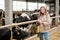 Female livestock farmer standing against cows