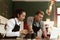 Female and male barista talking order on mobile phone and laptop computer while standing behind coffee shop counter bar, waitress