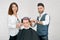 Female and male hairstylists doing haircut for young client with toned hair.