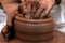 Female or male hands form a bowl on a spinning pottery wheel. Work with red clay. Traditional hand made dishes. Shallow depth of