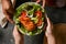 Female and male hands holding grilled chicken breast fillet salad