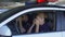 Female and male police officers putting on sunglasses sitting in patrol car, law