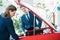 Female and male Sales managers of a car showroom looking under open car