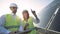 A female and a male solar inspectors are having a discussion near a solar module. Green energy concept.