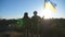 Female and male soldier of ukrainian army standing at peak of hill with raised flag of Ukraine. Military couple in