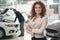 Female manager posing in car showroom.