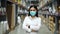 Female manager wearing medical mask with arms crossed in warehouse store during coronavirus covid-19 pandemic