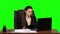 Female manager works on a laptop, think and takes notes. Green screen background. Slow motion