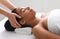 Female masseuse massaging relaxed black lady head