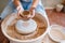 Female master holds wet pot over the pottery wheel