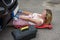 Female mechanic on a crawler to access underside of a automobile.