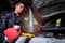 Female mechanic with motor oil gallon working in garage, car service technician checking and repairing customer car at automobile