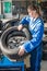 Female Mechanic Mounting Car Tire On Rim In Garage