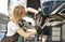 Female mechanic repairing vehicle brake disc.