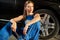 Female mechanic sits near the tire holding a wrench