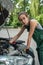 female mechanic wear green uniform checking level of oil on a car engine dipstick