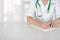 Female medical doctor with clipboard standing over blurry hospital background