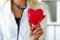 Female medicine doctor wearing hold in hands red toy heart