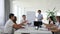 Female mentor near Whiteboard with chart speaks with colleagues about business development into boardroom