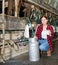 Female milker posing with glass of milk on dairy farm