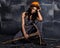 female miner worker with pickaxe, in coveralls over his naked body, sitting on the floor on backdrop of steel wall