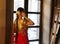 Female model Indian Bride in saree, wearing gold and jasmine flower garlands in the hair near mirror, back view.