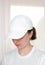 Female model wearing a white baseball cap. White cap mockup, template for picture, text or logo. Girl holding visor of