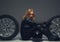 Female with motorcycle helmet sitting between two car wheels.