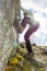 Female mountaineer practicing boulder climbing outdoor on large boulder.