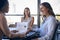 Female Multi-Cultural Business Team Meet Around Boardroom Table With Laptops Discussing Documents