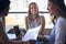 Female Multi-Cultural Business Team Meet Around Boardroom Table With Laptops Discussing Documents