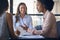 Female Multi-Cultural Business Team Meet Around Boardroom Table With Laptops Discussing Documents