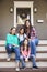 Female Multi Generation Family Sit On Steps in Front Of House