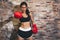 Female muscular sport boxer with boxing gloves posing over wall