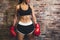 Female muscular sport boxer with boxing gloves posing over wall