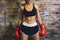 Female muscular sport boxer with boxing gloves posing over wall brick background.