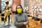 Female museum visitor in protective mask examining ancient armor