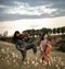 Female musical duet with violin and cello plays on meadow.