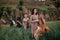 Female musical quartet with violins and cello prepares to play at flowering meadow.