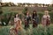 Female musical quartet with violins and cello prepares to play at flowering meadow.