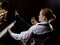 Female musician dressed in a man`s suit sitting next to the piano and drinks champagne