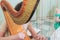 Female musician harpist playing wooden harp  during symphonic concert on a stage, with other musicians in the background, close up