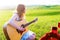 Female musician sitting on green grass playing acoustic guitar and singing songs. Talented girl relaxing at green spring or summer