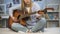 Female musician tuning the guitar on home sofa, enjoying melody, practicing