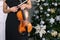 Female musician violinist with her violin on the Christmas tree background